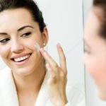 Young woman caring of her skin standing near mirror in the bathr