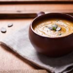 Homemade tasty creamy pumpkin soup puree in a bowl on a wooden background